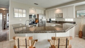 A modern kitchen with granite countertops, white cabinetry, and a central island.