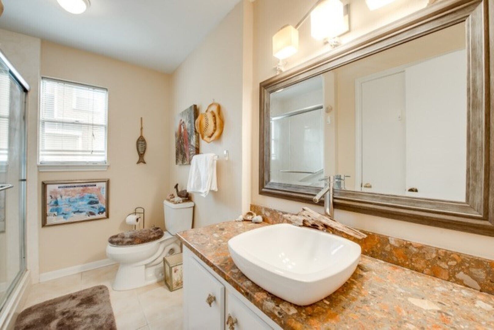 A bathroom with a large mirror, a white sink, and a toilet.