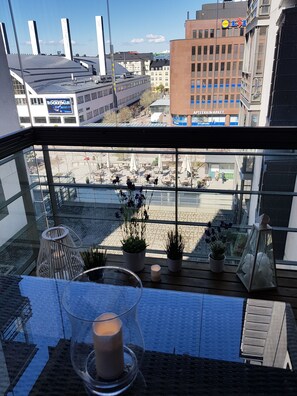 A balcony with potted plants, a glass table, and a candle.