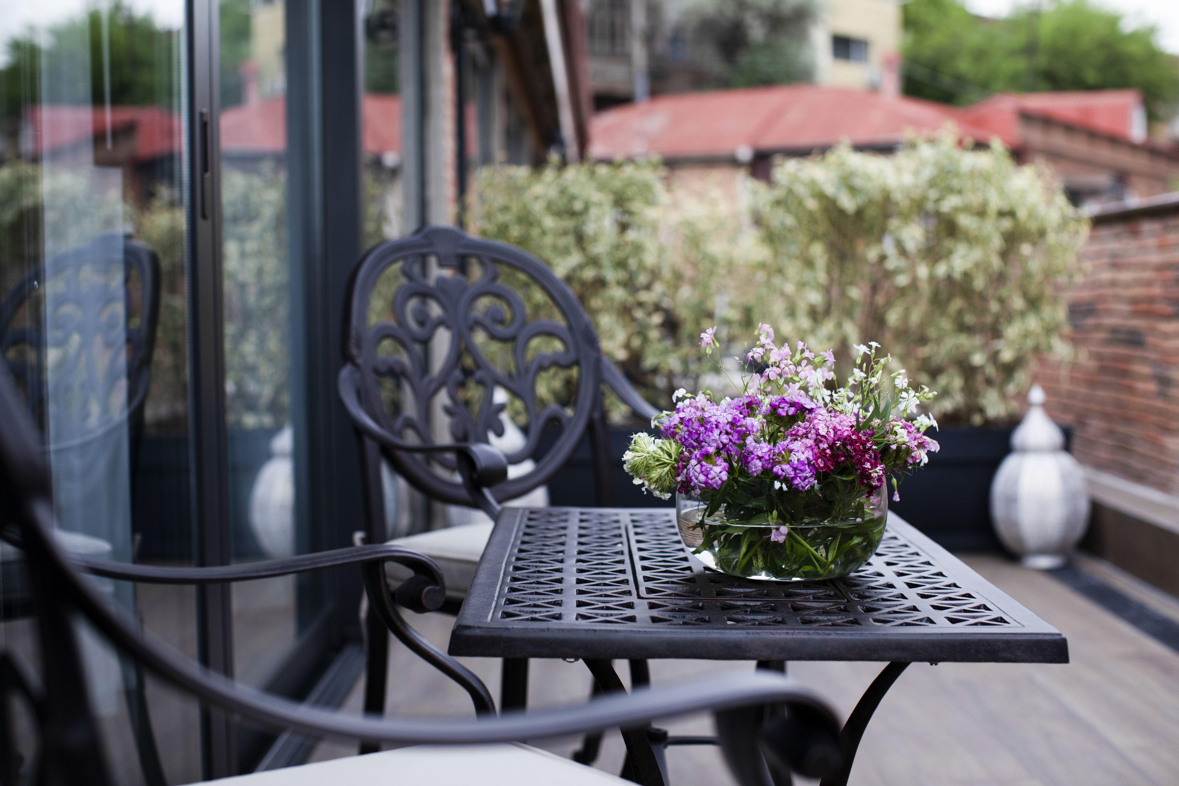 Et metalbord med en vase blomster på en balkon.