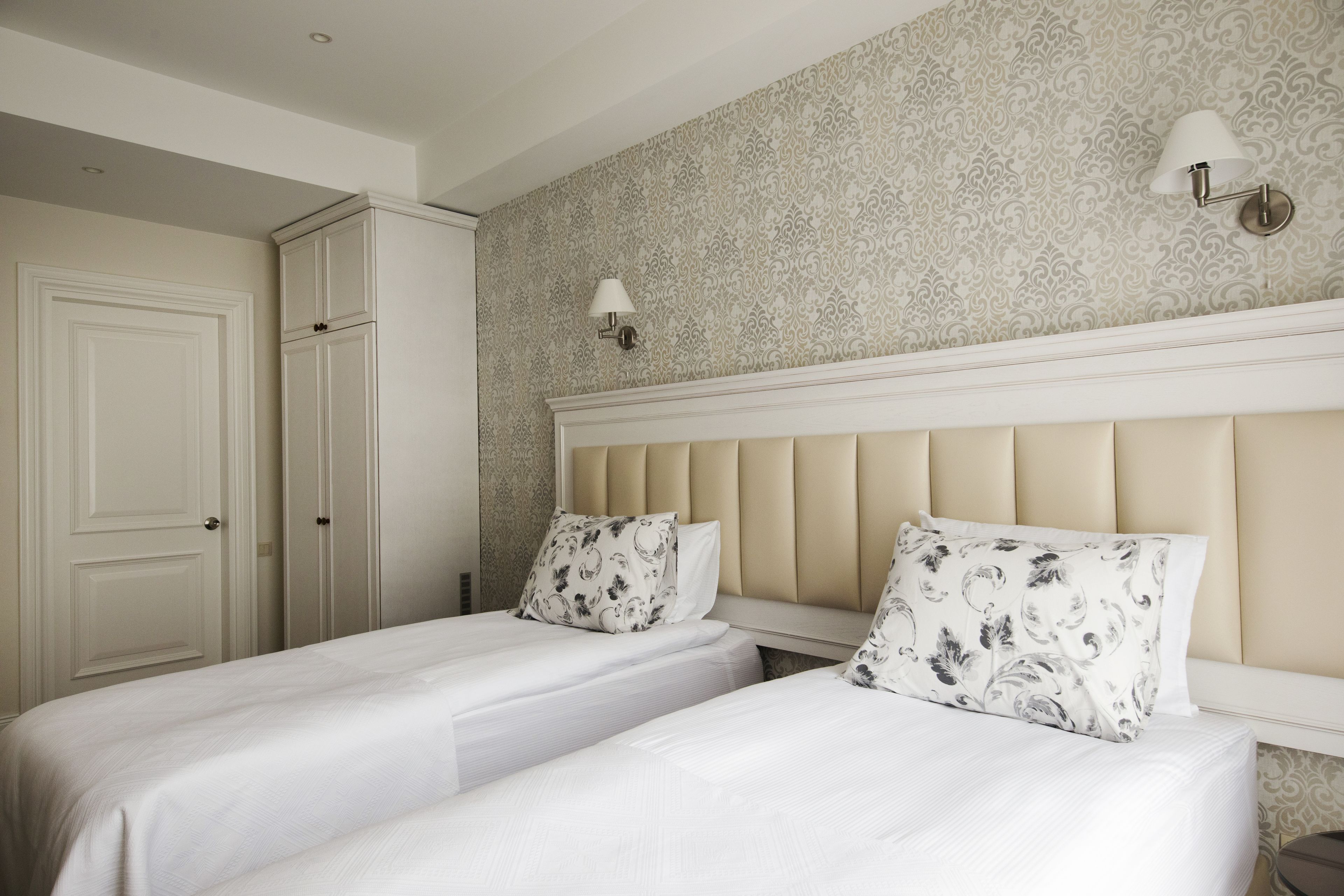 Une chambre avec deux lits, une armoire et un papier peint à motifs.