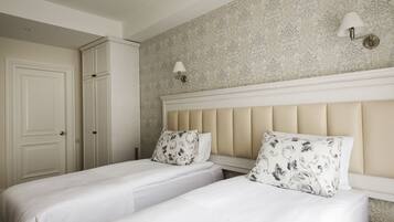 A bedroom with two beds, a wardrobe, and patterned wallpaper.