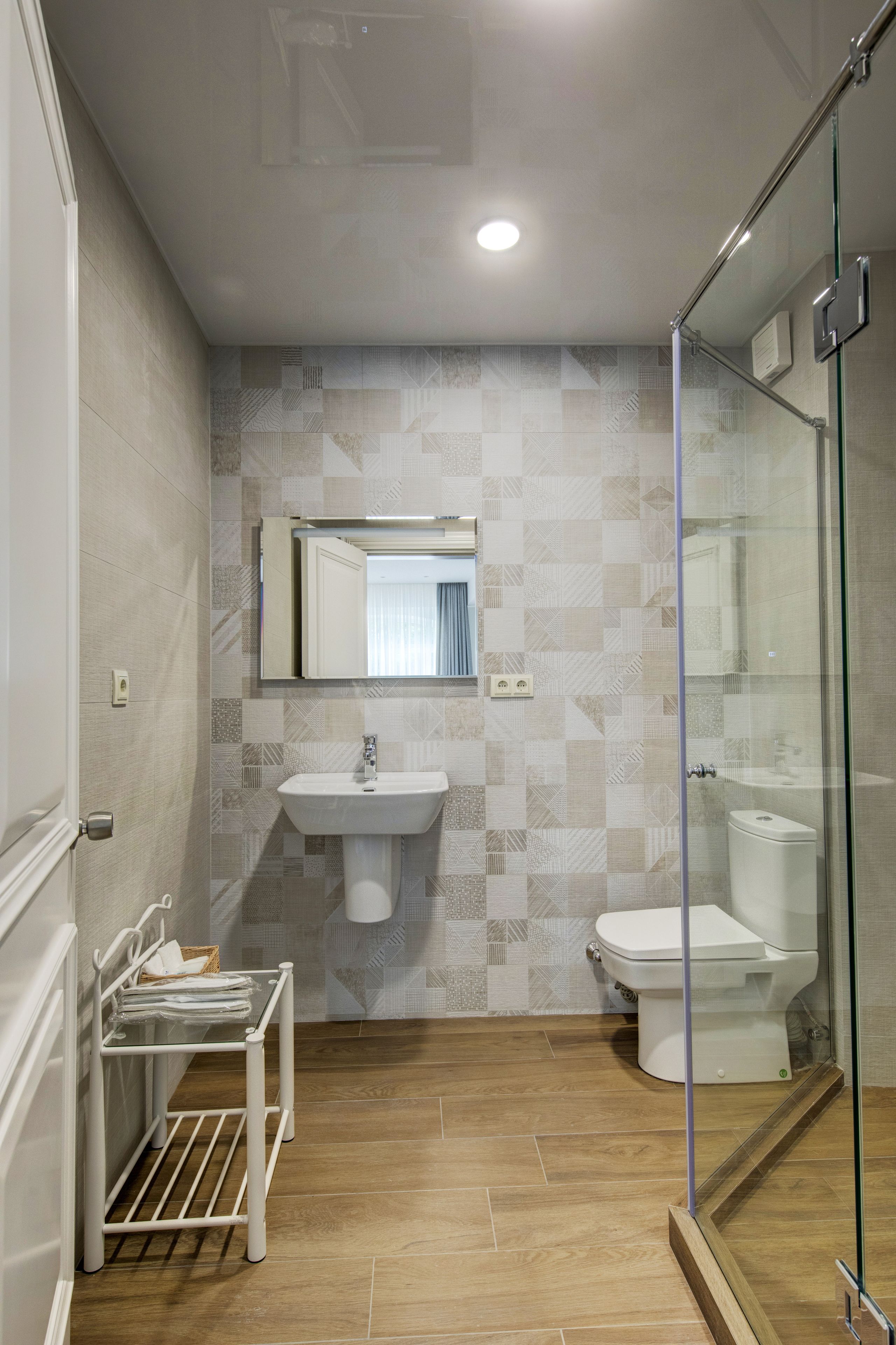 A bathroom with a glass shower enclosure, a sink, and a toilet.