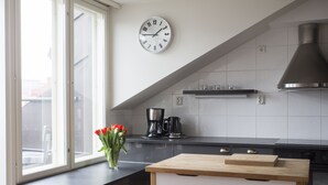 A modern kitchen with a clock, a coffee maker, and a vase of red tulips on the counter. - 2ndhomes 2BR Penthouse with Balcony and Sauna (Helsinki)