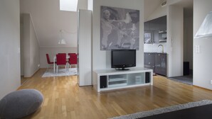 A modern living room with a flat-screen TV, red chairs, and a dining area with a white table. - 2ndhomes 2BR Penthouse with Balcony and Sauna (Helsinki)
