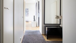 A hallway with a grey carpet, a black console table, a large mirror, and a white door. - 2ndhomes 2BR Penthouse with Balcony and Sauna (Helsinki)