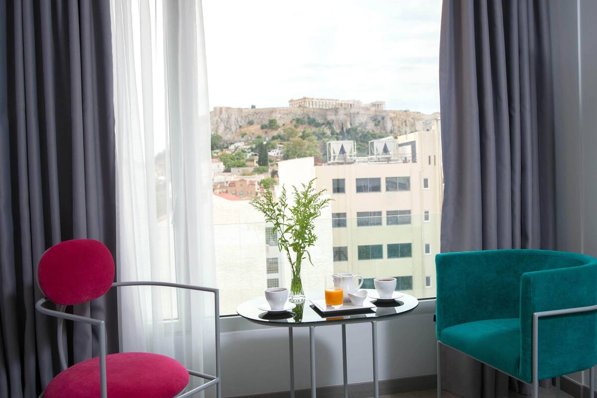 Una habitación con vistas a un sitio histórico, una mesa con un jarrón y tazas, y dos sillas.