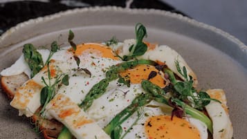 A plate with poached eggs, asparagus, and greens on a textured ceramic plate.