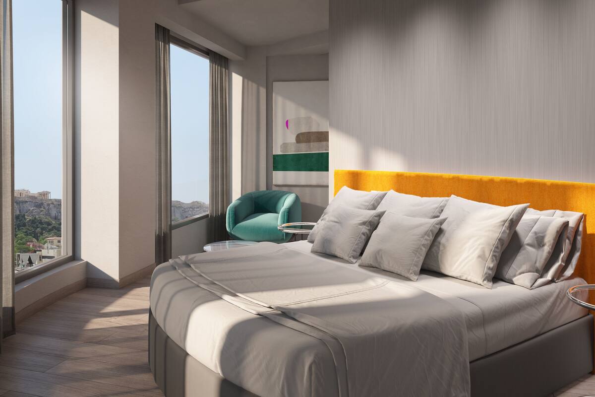 Un dormitorio moderno con una cama grande, una silla color turquesa y vistas de la ciudad a través de amplios ventanales.