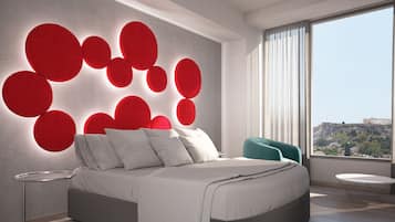 A modern bedroom with a large bed, a round side table, a chair, and a wall with circular light fixtures.