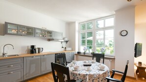 Una cocina moderna con armarios grises, encimera de madera y una mesa de comedor preparada para cuatro personas.
