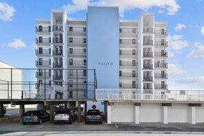 Un edificio residencial de varios pisos con balcones, un estacionamiento y un letrero que dice 'SAILS II'.