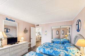 Une chambre à coucher avec un lit, une commode, un téléviseur et un miroir.