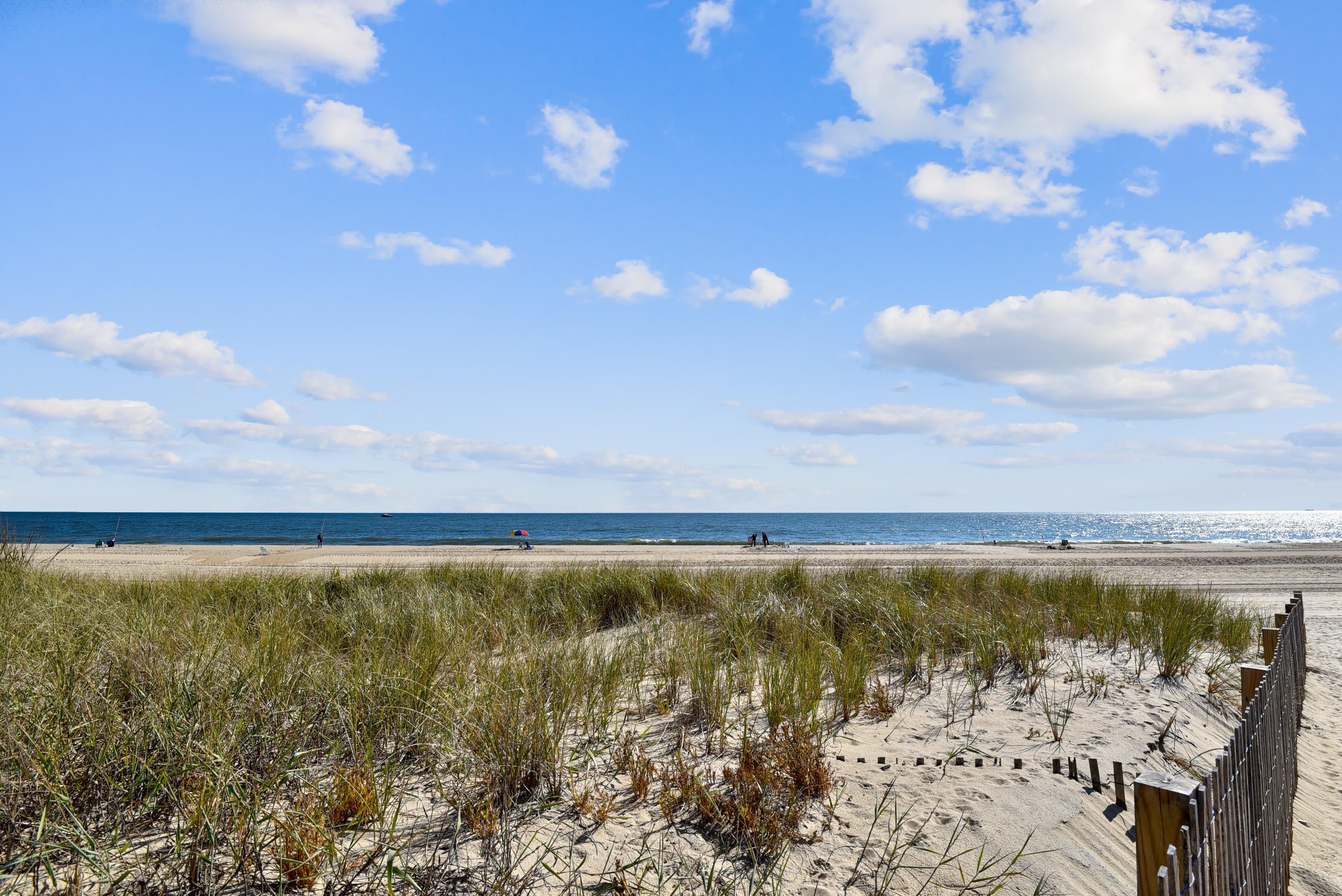 Ein Strand mit einer Holzumzäunung, Dünen und dem Meer.