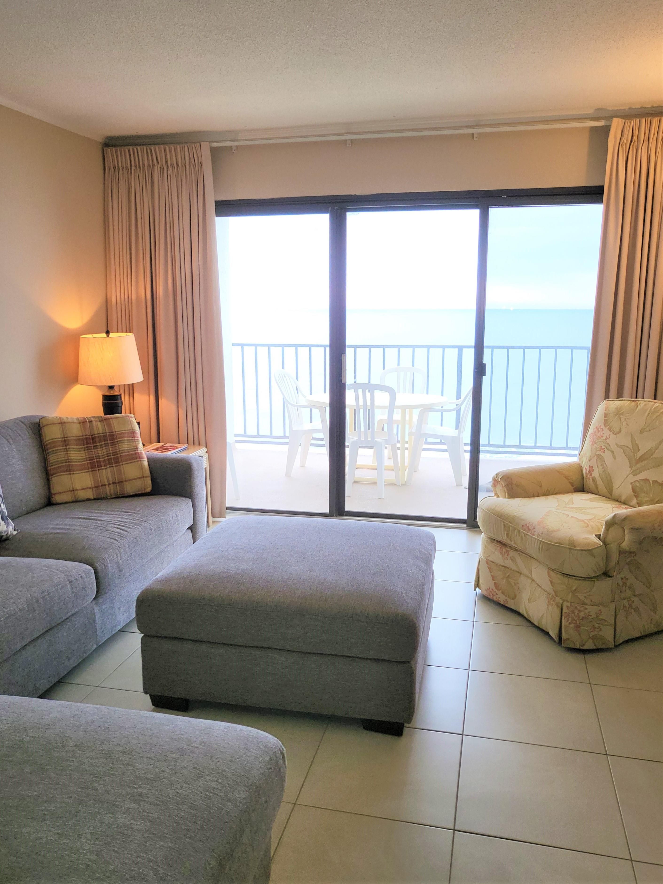 Une chambre d’hôtel comprenant un canapé, un pouf, un fauteuil et une table avec des chaises.