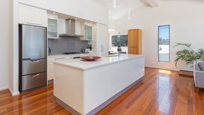 A modern kitchen with a central island, stainless steel appliances, and a large window providing a view of the outdoors.