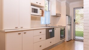 Een keuken met witte kastjes, een magnetron, een vaatwasser en een inbouwoven.