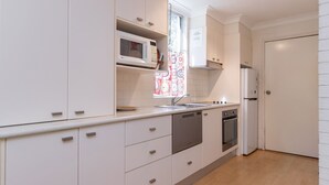 A modern kitchen with white cabinets, a microwave, a sink, a stove, and a dishwasher. - Bella Villa Manyana 19 great location short stroll to the beach and local shops (Blueys Beach)