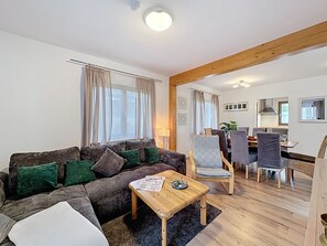 A living room with a sofa, a coffee table, and a dining area with chairs and a table.