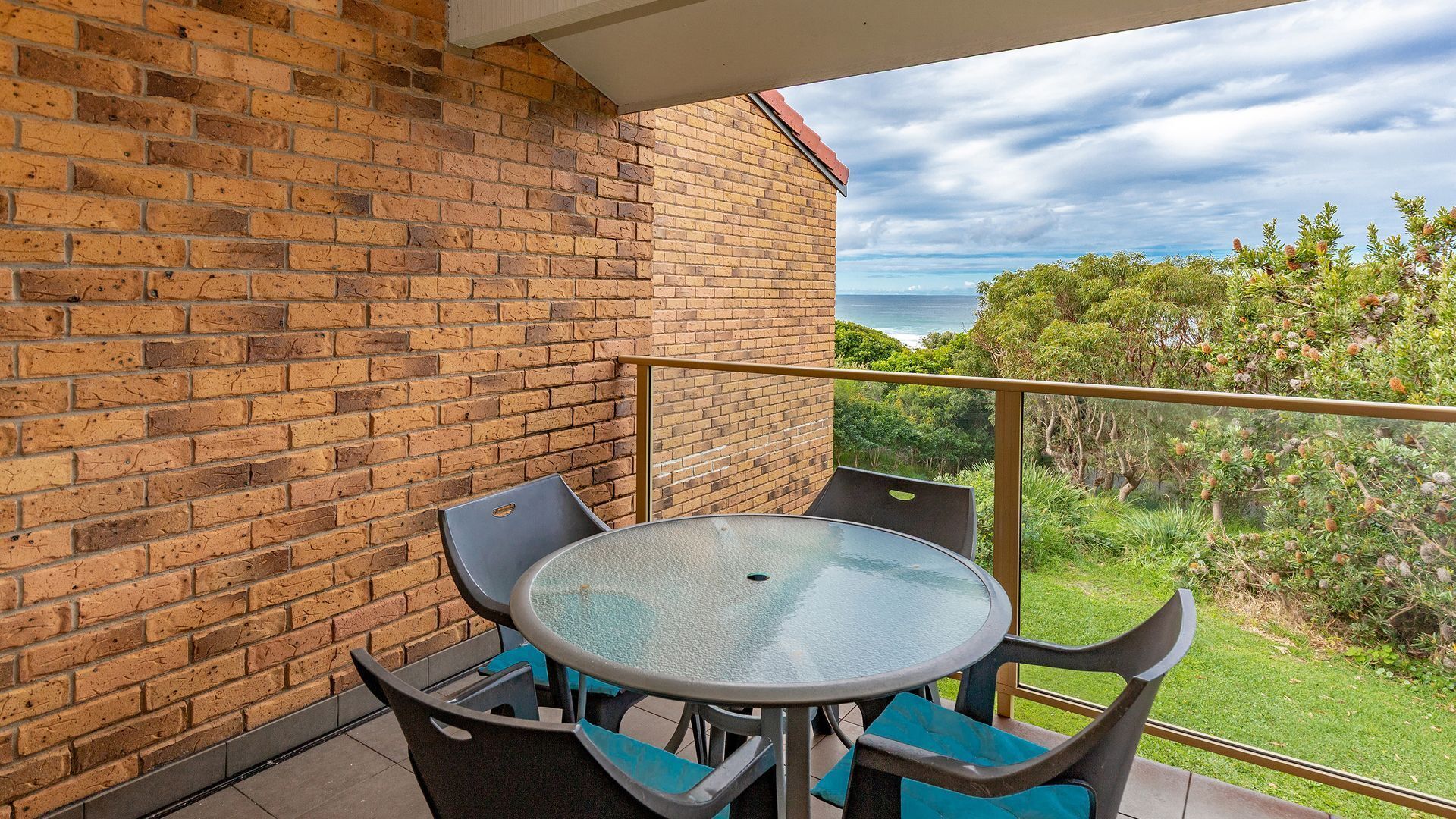 Un balcon avec un mur en briques, une table ronde et deux chaises.