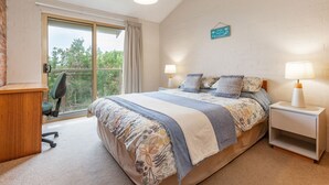 A bedroom with a large bed, two bedside tables with lamps, a desk, and a chair.