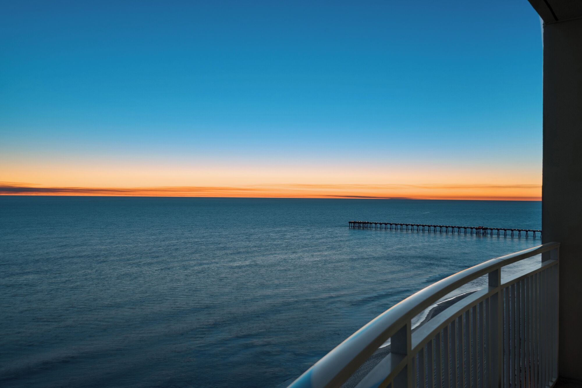 A view of the ocean with a pier extending into the water.