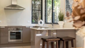 A modern kitchen with stainless steel appliances, a large window, and a view of greenery outside. - Boom 8 - Boomerang Beach (Boomerang Beach)