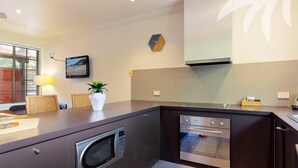 A modern kitchen with a built-in oven, microwave, and a large island with seating. - Aqua Apartment #2 - Pacific Palms Holidays (Blueys Beach)
