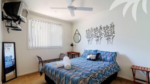 A bedroom with a bed, a desk, a chair, a ceiling fan, and a window with blinds. - Aqua Apartment #2 - Pacific Palms Holidays (Blueys Beach)
