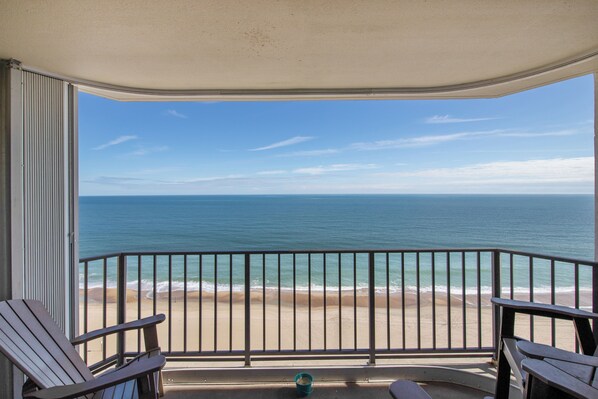 A balcony with a view of the beach and ocean.