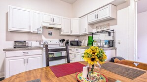 A compact kitchen with white cabinets, a microwave, a toaster, and a sink. - Funky Home Away from Home  (New Orleans)