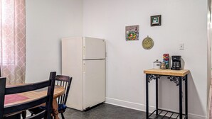 A compact kitchenette with a refrigerator, a small table with a coffee maker, and a chair. - Funky Home Away from Home  (New Orleans)
