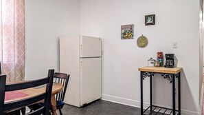 A compact kitchenette with a refrigerator, a small table with a coffee maker, and a chair. - Funky Home Away from Home  (New Orleans)