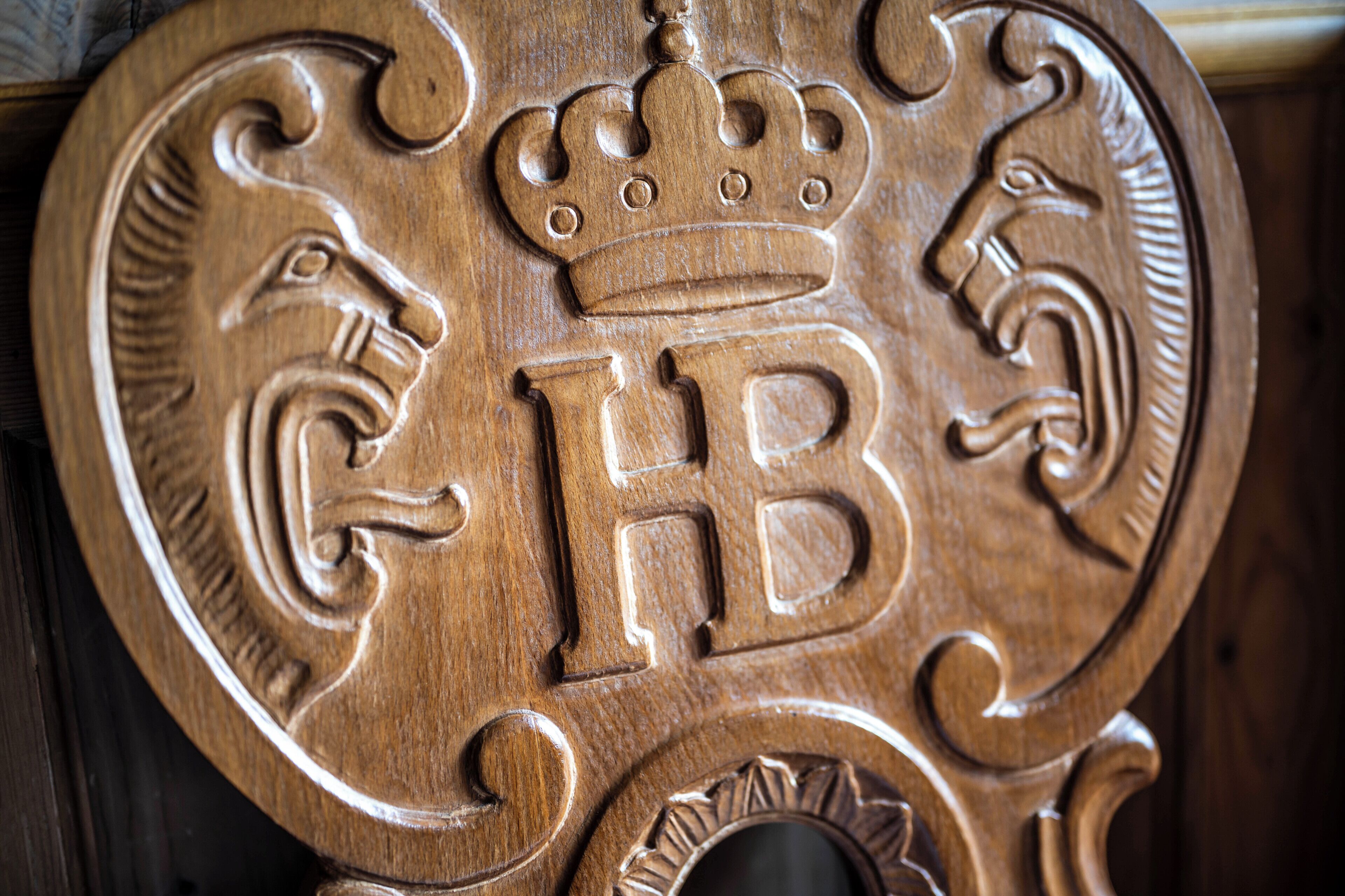 A wooden plaque with a crown, a lion, and the letters 'GB' carved into it.