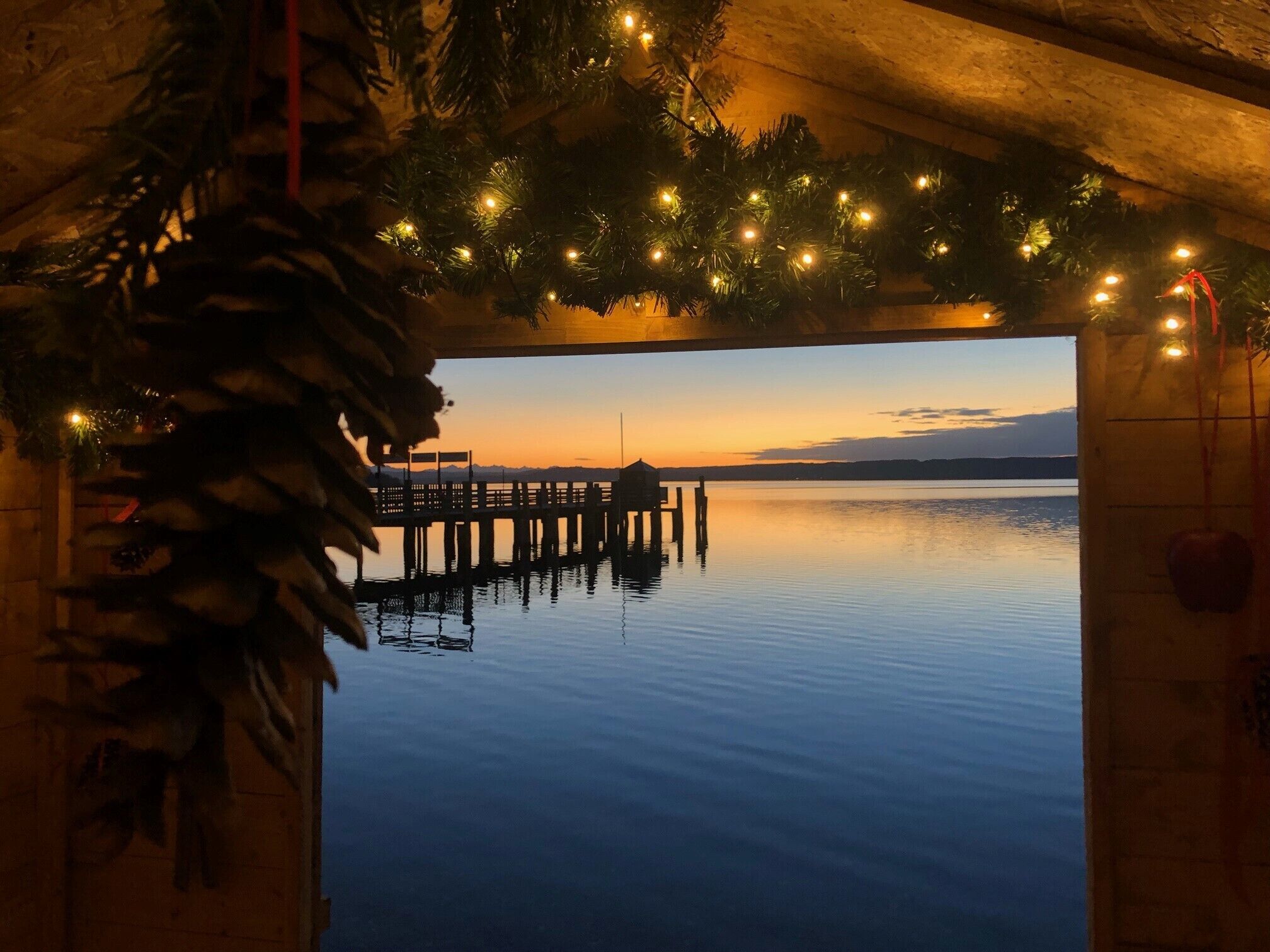 Vista al agua con un muelle que se adentra en aguas tranquilas, decorado con guirnaldas luminosas.