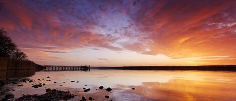 Un atardecer sobre un lago tranquilo con un muelle que se adentra en el agua.