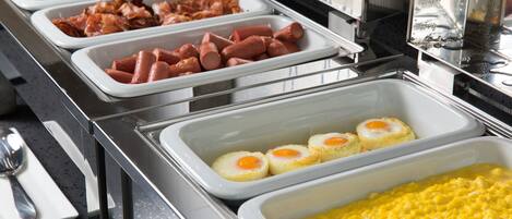 Un buffet proposant une variété de plats, notamment des hot-dogs, des œufs et des œufs brouillés.