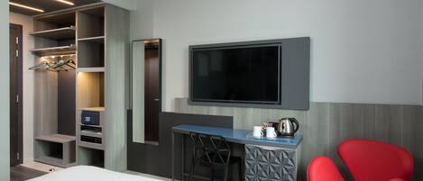 A hotel room with a bed, a desk with a chair, a TV, and a wardrobe.