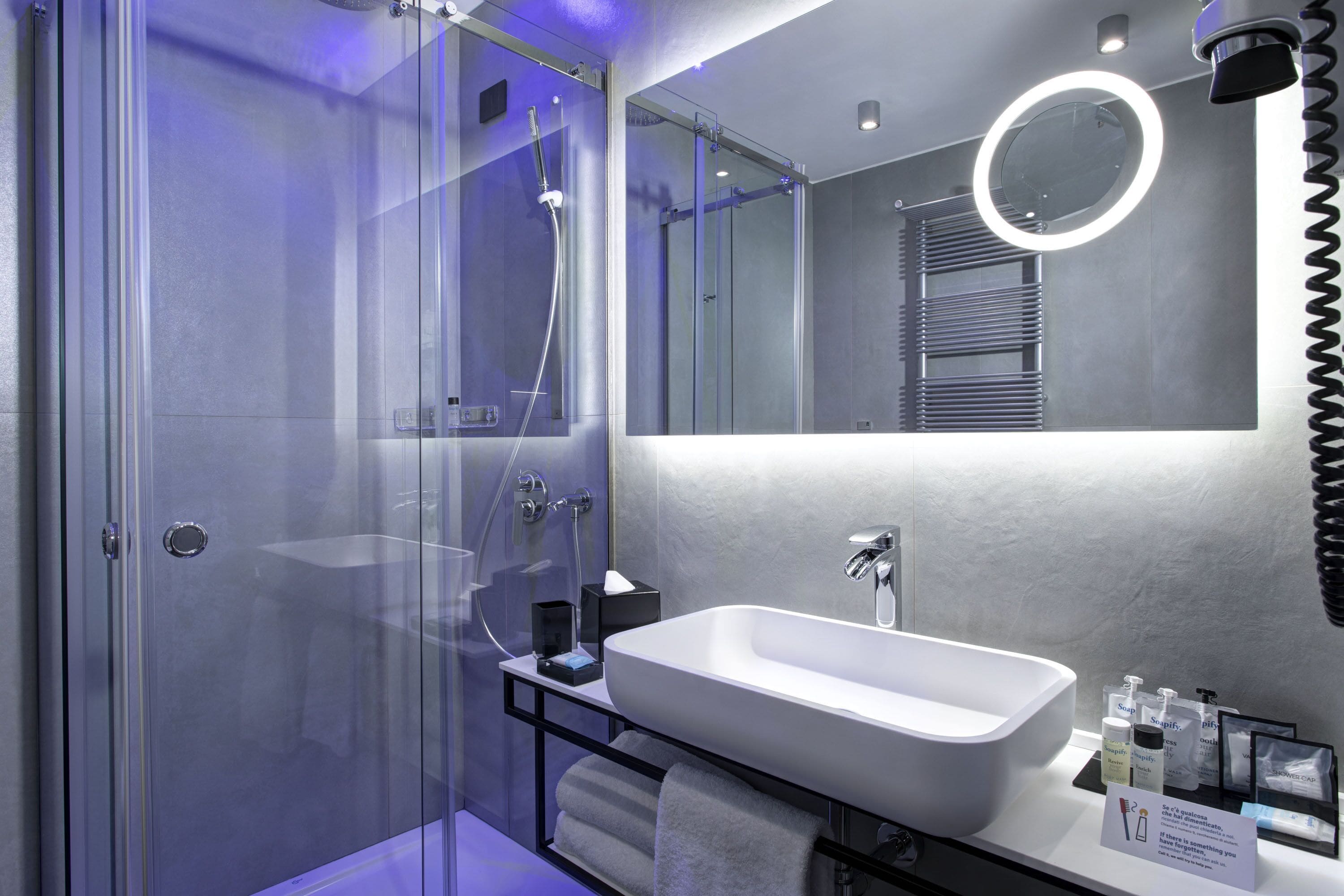 Une salle de bain moderne avec une douche à parois de verre, un lavabo blanc et un meuble-lavabo avec des articles de toilette.