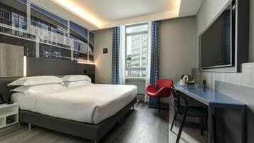 A hotel room with a bed, a desk, a chair, a TV, and a large window.