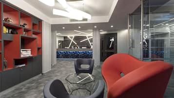 A modern office space with a reception desk, two chairs, and a glass partition.