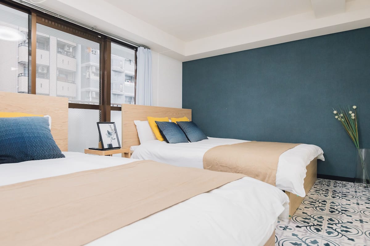 A hotel room with two beds, a large window, and a view of a building.