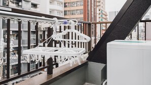 A balcony with a white drying rack and a white air conditioning unit. - AFP Shimanouchi J Apartment (Osaka)