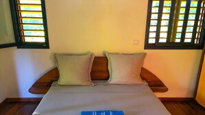 A bed with two pillows, a blue name tag, and a small plant.