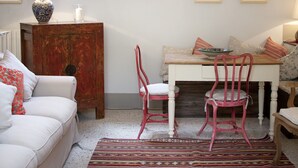 Ein gemütliches Zimmer mit einem weißen Sofa, einem Holztisch, einem roten Sessel und einem gemusterten Teppich.