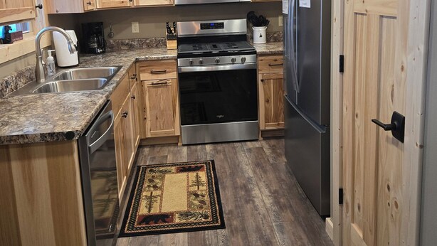 Une cuisine avec des meubles en bois, un four à micro-ondes en acier inoxydable, une cuisinière et un réfrigérateur.