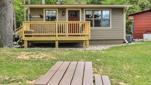 Une petite cabane avec une terrasse en bois et une table de pique-nique devant.