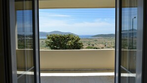 A balcony with a view of a landscape, including a tree and distant hills. - Villa Xenia (Saronikos)