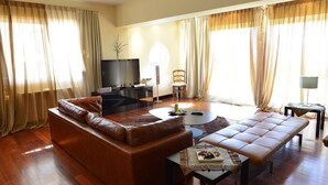 A living room with a leather sofa, a coffee table, and a flat-screen TV. - Villa Xenia (Saronikos)