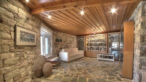 Ein Zimmer mit Steinwänden und Holzboden, ein weißes Sofa, eine Bank und eine Vitrine mit diversen Gegenständen.